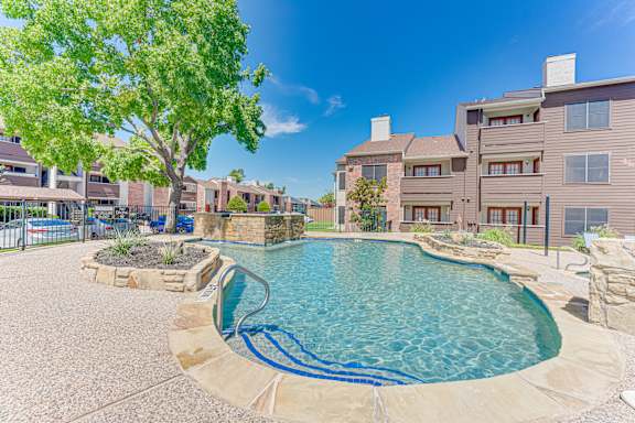 swimming pool surrounded by a stone patio at Timberglen Apartments, Dallas