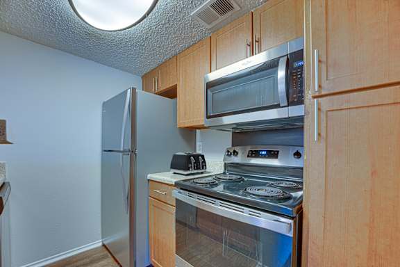 kitchen with a stove, microwave, and refrigerator at Timberglen Apartments, Dallas, TX