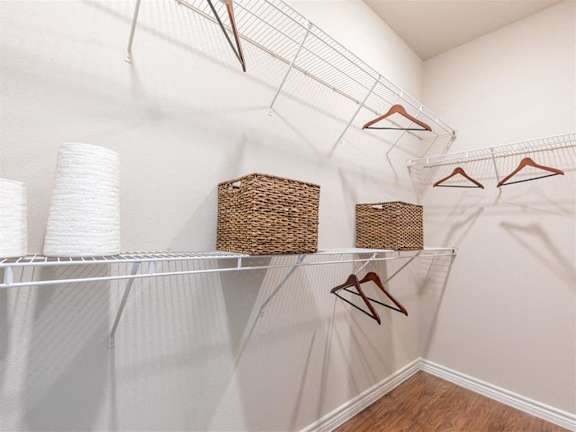 A white closet with clothes hanging on hangers.