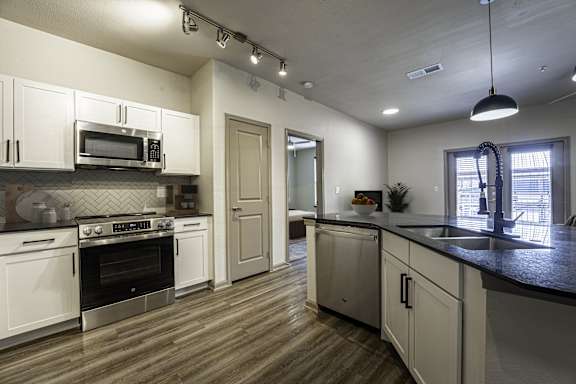 A modern kitchen with white cabinets and a black countertop.