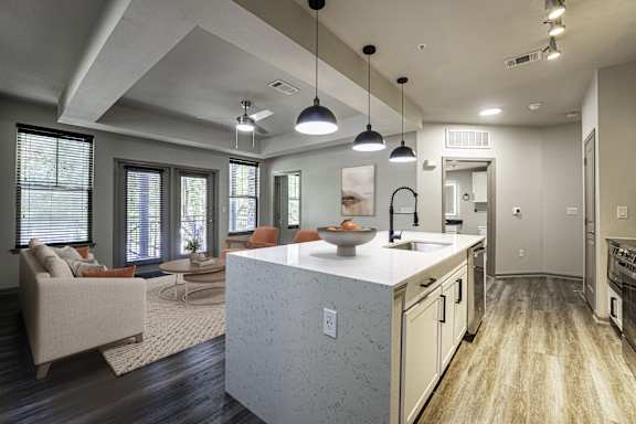 A modern kitchen with a large island and pendant lights.