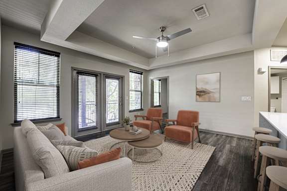 A living room with a couch, chairs, and a rug.
