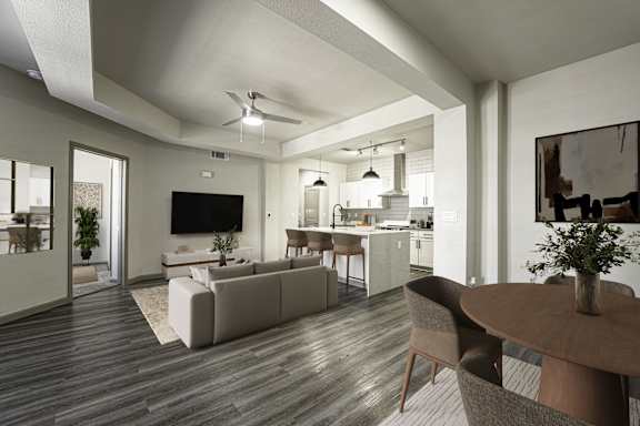 A modern living room with a flat screen TV, a dining table and chairs, and a kitchen area in the background.