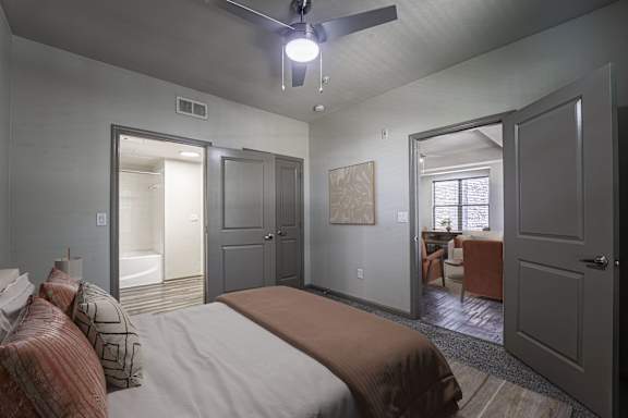 A bedroom with a bed, a ceiling fan, and a window.