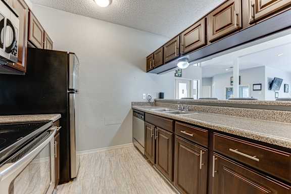 A kitchen with brown cabinets and a black refrigerator. at Wilson Crossing, Cedar Hill, 75104