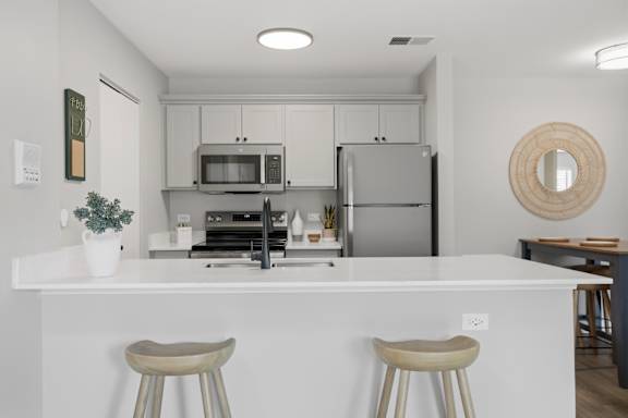A white kitchen with a white counter and two stools.