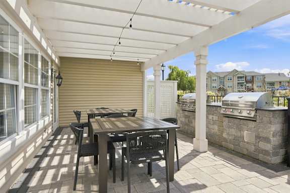 A patio with a table and chairs under a white pergola.