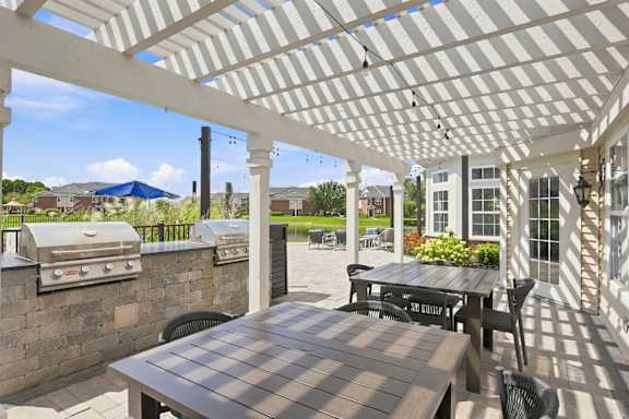A patio with a table and chairs under a white pergola.