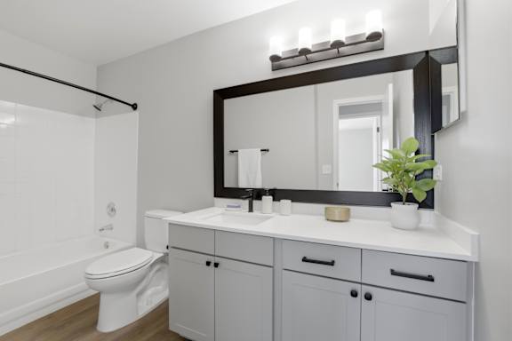 A white bathroom with a toilet, sink, and mirror.