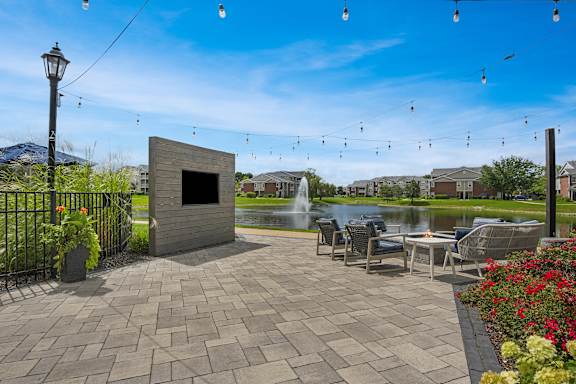 A patio area with a table and chairs and a fountain in the background.