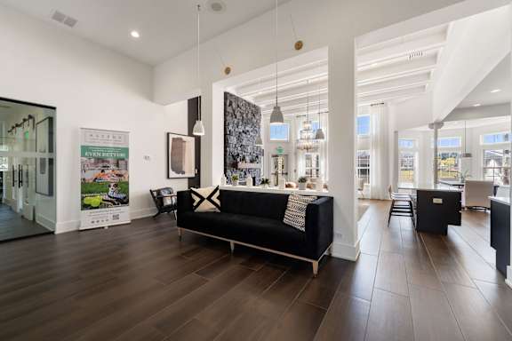 A modern living room with a black couch and wooden floors.
