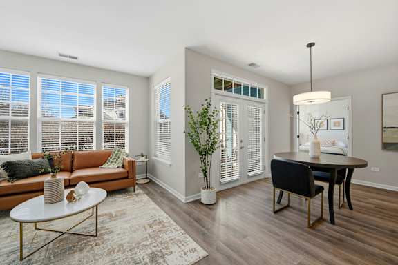 A living room with a brown couch, a coffee table, and a dining table.