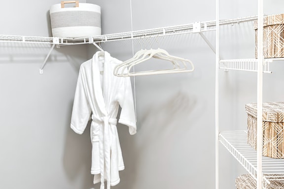 A white robe is hanging on a white hanger.