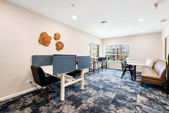 A room with a blue carpet and a white table with chairs.