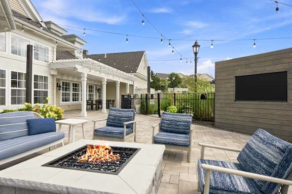 A patio with a fire pit and chairs.