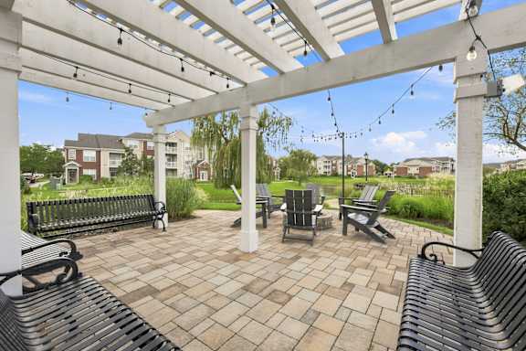A white pergola with benches and a table underneath it.