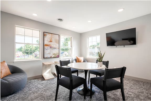 A modern living room with a grey sofa, a white table, and a flat screen TV mounted on the wall.