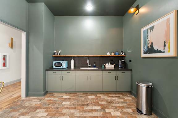 A kitchen with a tiled floor and a green wall.