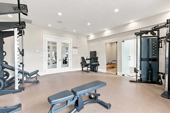 A spacious gym with a variety of equipment including a squat rack, a bench, and a weight machine.