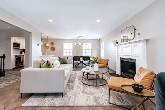 A modern living room with a white sofa, a coffee table, and a fireplace.