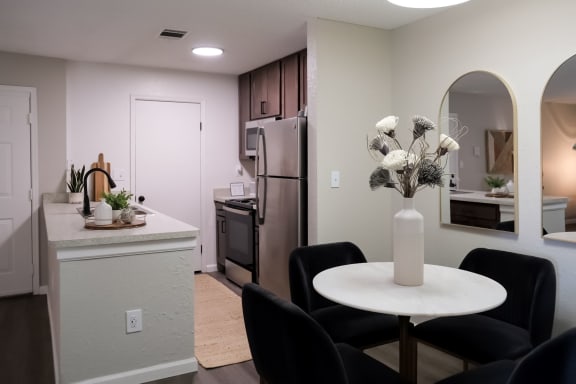 a dining area with a small white table and four black chairs