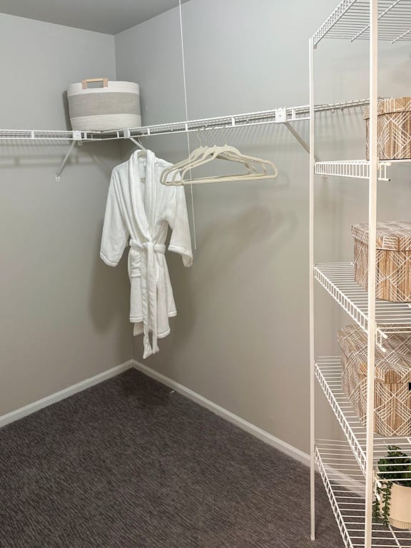 a walk in closet with a white robe hanging on the wall
