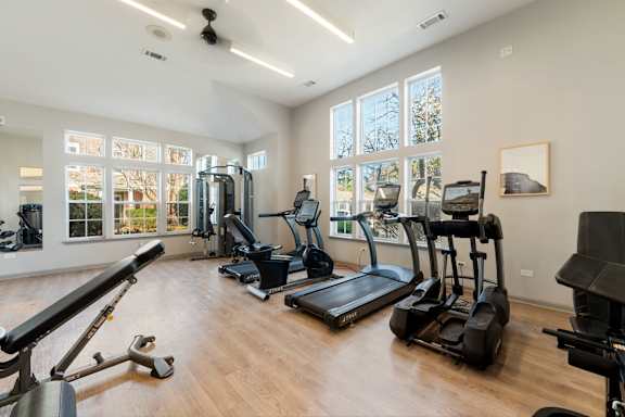 A spacious gym with a variety of exercise equipment and large windows.
