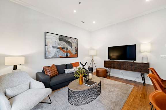 A living room with a grey couch, a white chair, a coffee table, and a painting on the wall.