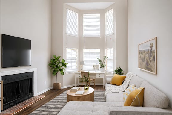 A living room with a grey couch, a fireplace, and a painting on the wall.