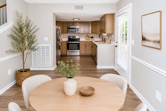 A dining room with a table and chairs and a tree in a pot.