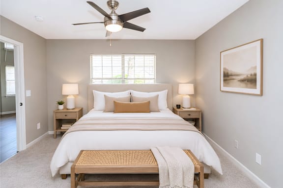A bedroom with a large bed and a ceiling fan.