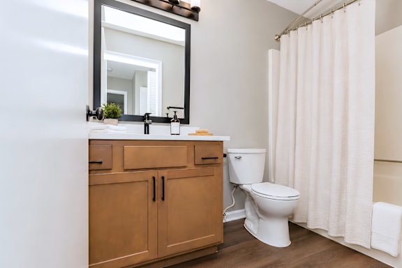 A bathroom with a toilet, sink, and mirror.