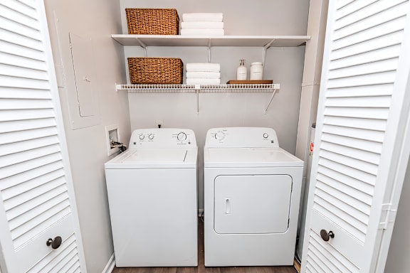 A small bathroom with two toilets and a shelf above them.