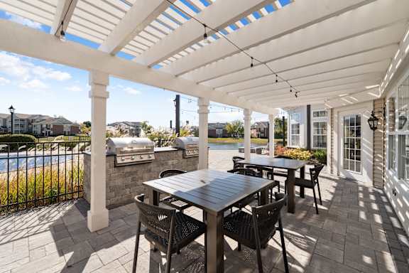 A patio with a table and chairs under a white pergola.