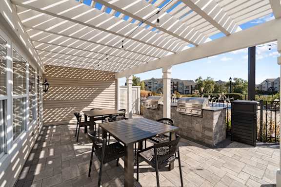 A patio with a table and chairs under a white pergola.