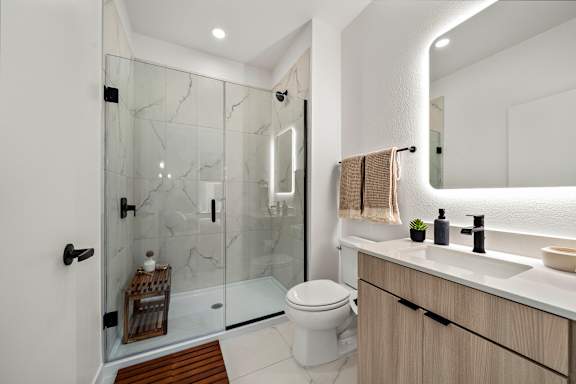 A modern bathroom with a glass shower and a white toilet.