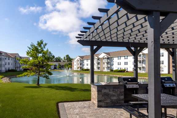 A patio with a table and chairs overlooking a pool.