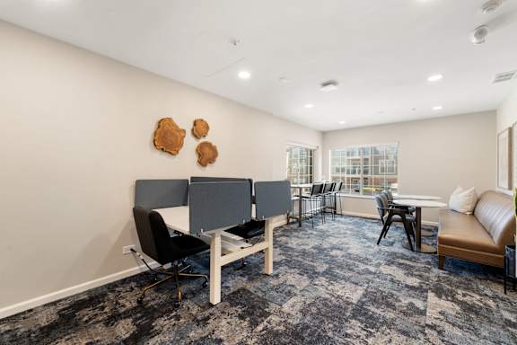 A room with a grey carpet and a white table with chairs.