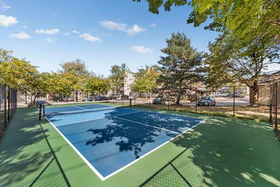 A tennis court surrounded by trees and a fence.