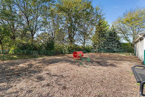 A backyard with a red object and a black bench.