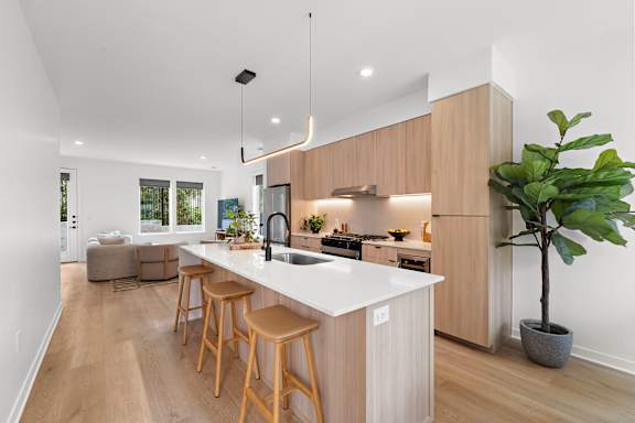 A kitchen with a white countertop and wooden stools.