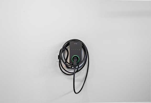A black device with a green light is plugged into a white surface.
