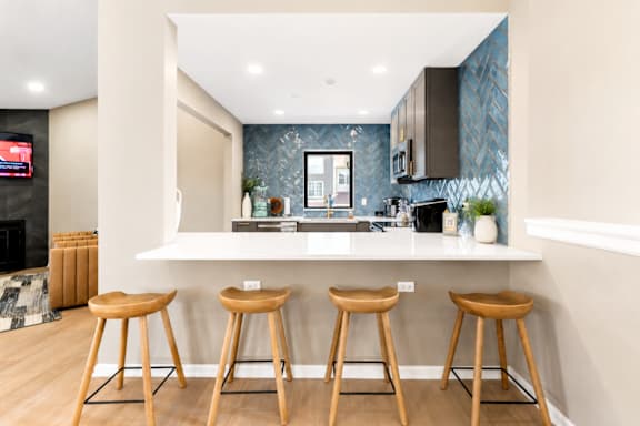 A kitchen with a bar area and three stools.