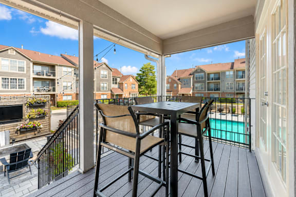 A patio with a table and chairs overlooking a pool.