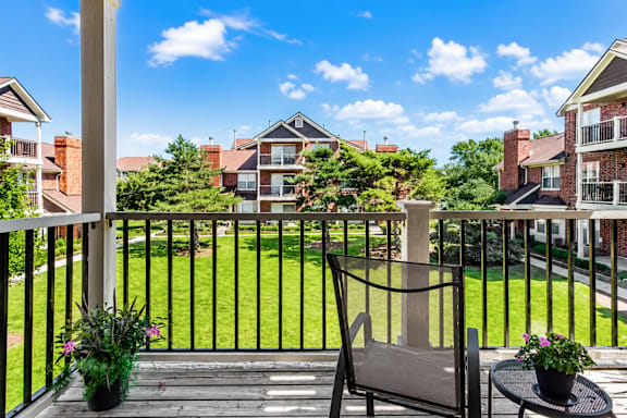 A balcony with a chair and table with flowers on it.