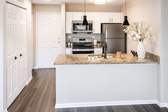 A kitchen with a refrigerator, oven, and sink.