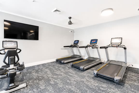 A gym with treadmills and a television.