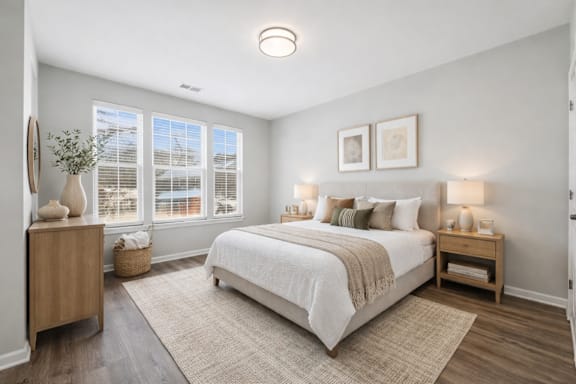 A bedroom with a large bed and a window with blinds.