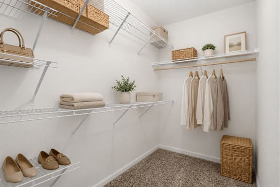 A white closet with clothes and shoes on shelves.