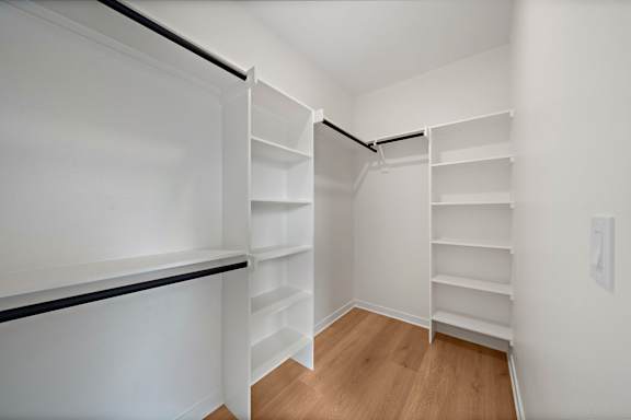 A white closet with shelves and a black rail.